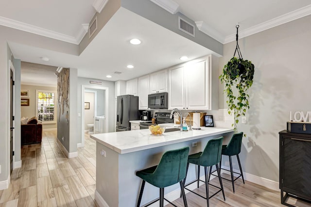 kitchen with a breakfast bar, kitchen peninsula, light hardwood / wood-style floors, white cabinetry, and stainless steel appliances