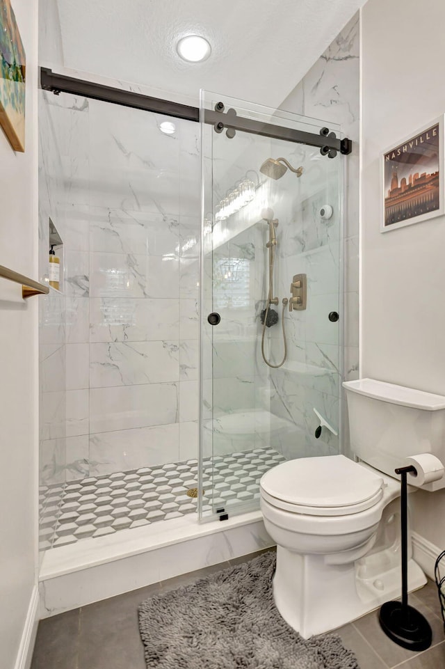 bathroom featuring tile patterned floors, toilet, and a shower with shower door