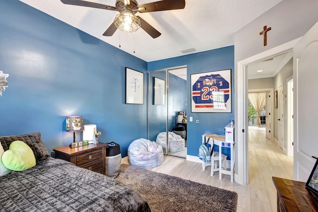 bedroom featuring a textured ceiling, light wood-type flooring, a closet, and ceiling fan