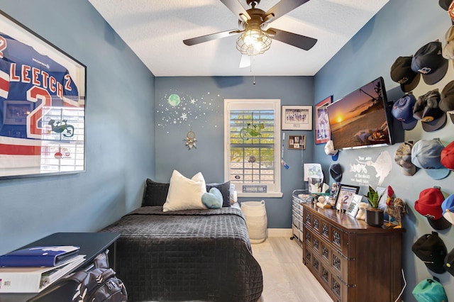 bedroom with ceiling fan, a textured ceiling, and light wood-type flooring