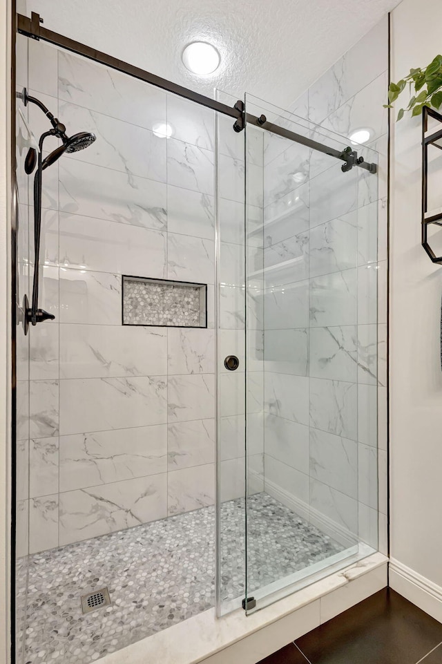 bathroom featuring tile patterned flooring, a shower with shower door, and a textured ceiling