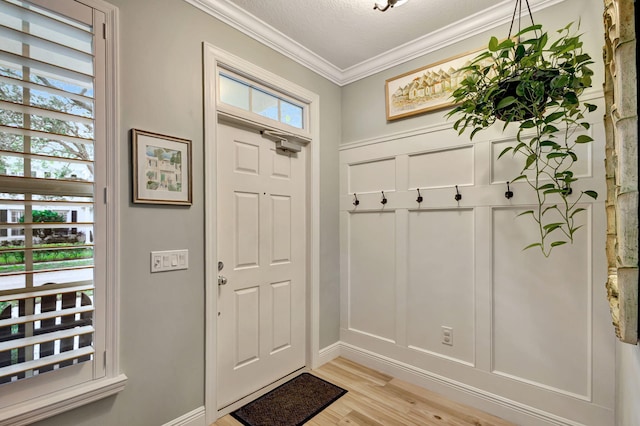 interior space with a textured ceiling, light hardwood / wood-style flooring, and crown molding