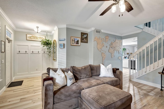 living room with a textured ceiling, light hardwood / wood-style flooring, ceiling fan, and ornamental molding