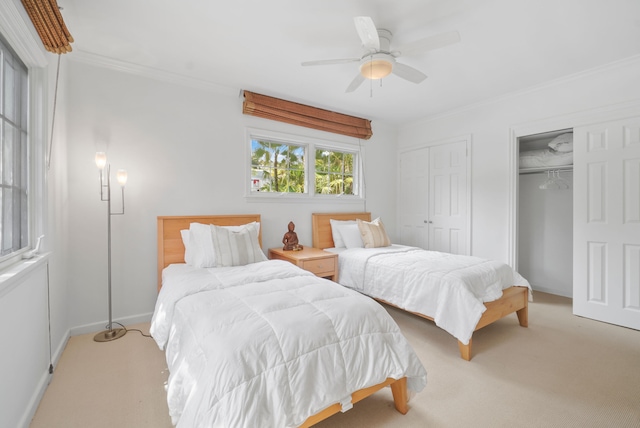 bedroom featuring light carpet, two closets, ceiling fan, and ornamental molding