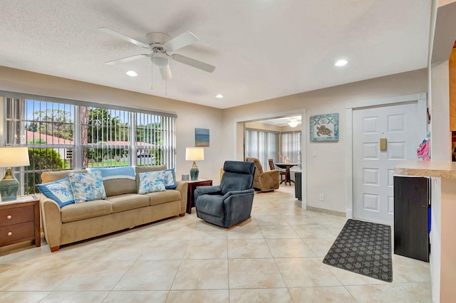 living room featuring ceiling fan, light tile patterned floors, and a textured ceiling