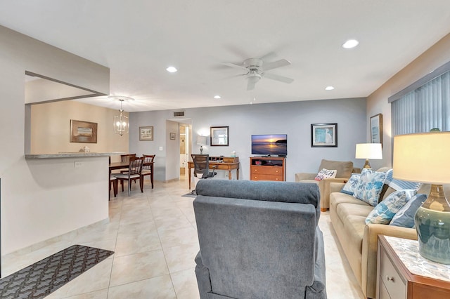 living room with light tile patterned floors and ceiling fan with notable chandelier