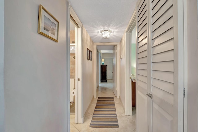 hallway featuring light tile patterned floors and a textured ceiling