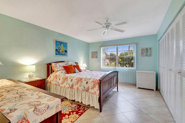 bedroom featuring light tile patterned floors, a textured ceiling, a closet, and ceiling fan