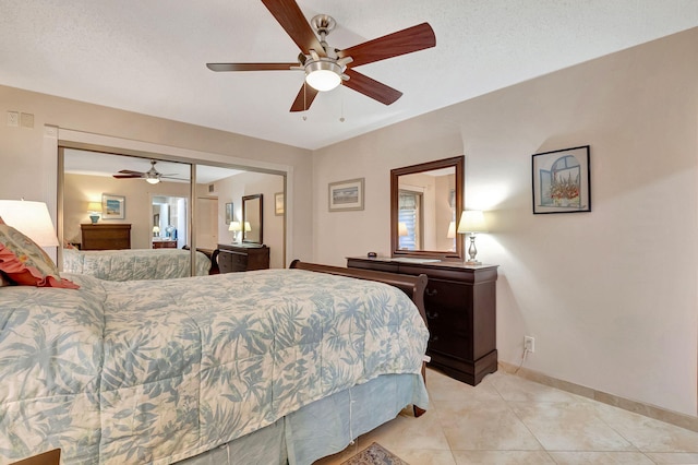 bedroom featuring a closet, ceiling fan, light tile patterned flooring, and a textured ceiling