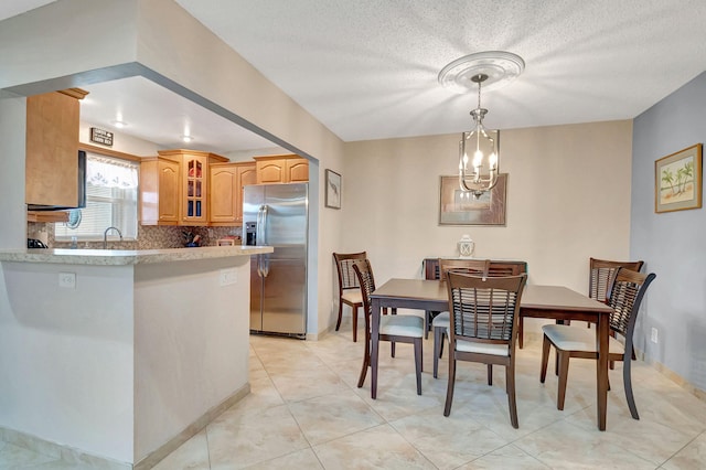 tiled dining space featuring an inviting chandelier and a textured ceiling