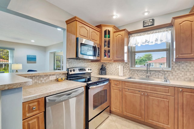 kitchen featuring decorative backsplash, appliances with stainless steel finishes, light tile patterned flooring, and sink