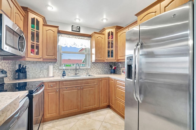 kitchen with sink, appliances with stainless steel finishes, light tile patterned floors, and tasteful backsplash