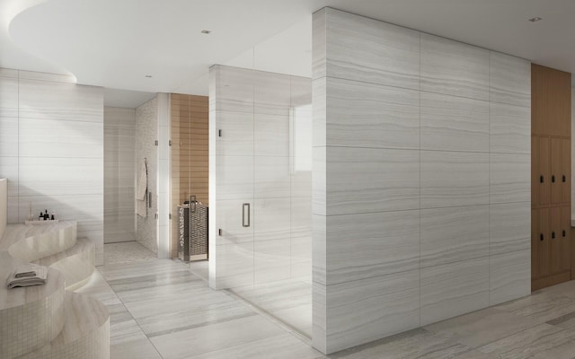 bathroom featuring tile patterned floors, a shower with door, and tile walls