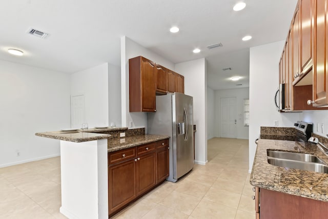 kitchen with kitchen peninsula, appliances with stainless steel finishes, sink, light tile patterned floors, and dark stone countertops