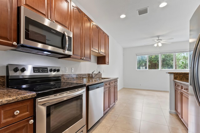 kitchen with stainless steel appliances, ceiling fan, dark stone countertops, and sink