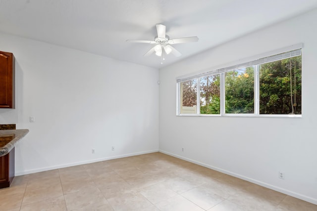 empty room with ceiling fan and light tile patterned floors