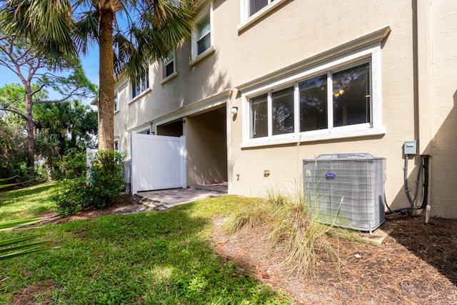 rear view of property featuring a yard and central AC unit