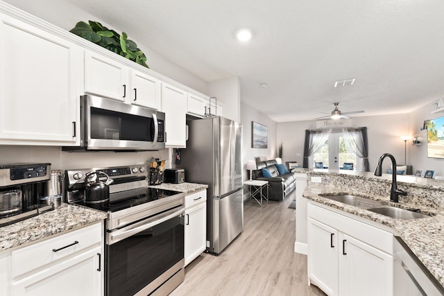 kitchen with stainless steel appliances, ceiling fan, sink, light hardwood / wood-style floors, and white cabinetry