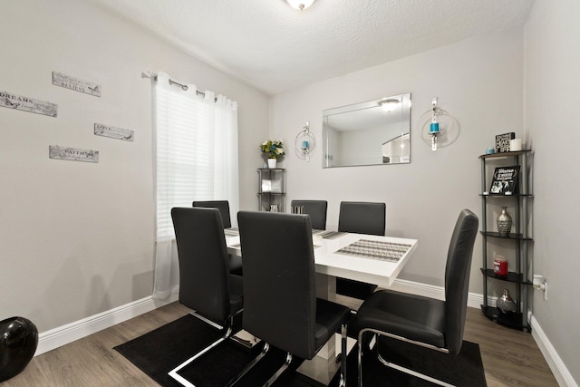 dining area with a textured ceiling and dark hardwood / wood-style flooring