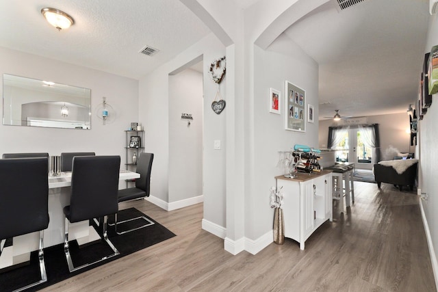 dining area featuring hardwood / wood-style floors, ceiling fan, and a textured ceiling