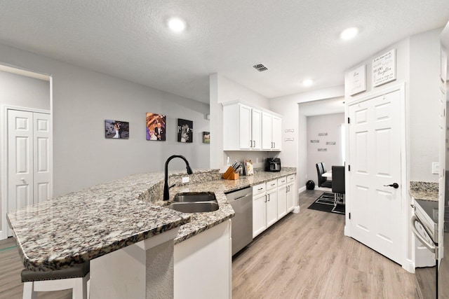 kitchen featuring sink, stainless steel dishwasher, stone countertops, light hardwood / wood-style floors, and white cabinetry