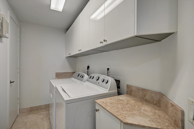 clothes washing area with cabinets, washer and dryer, and light tile patterned flooring