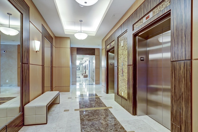 hall featuring a raised ceiling and elevator