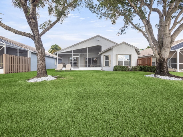 back of house featuring a sunroom and a lawn