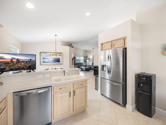 kitchen featuring stainless steel appliances, vaulted ceiling, sink, light brown cabinets, and hanging light fixtures