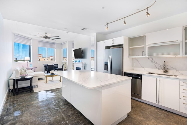 kitchen featuring sink, appliances with stainless steel finishes, a kitchen island, decorative backsplash, and white cabinets