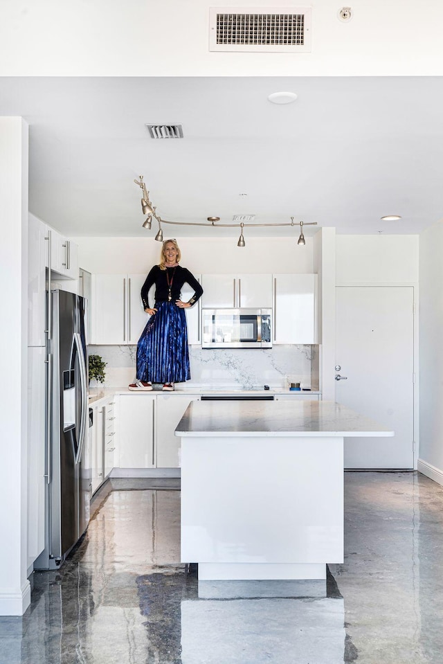 kitchen featuring appliances with stainless steel finishes, a center island, decorative backsplash, and white cabinets