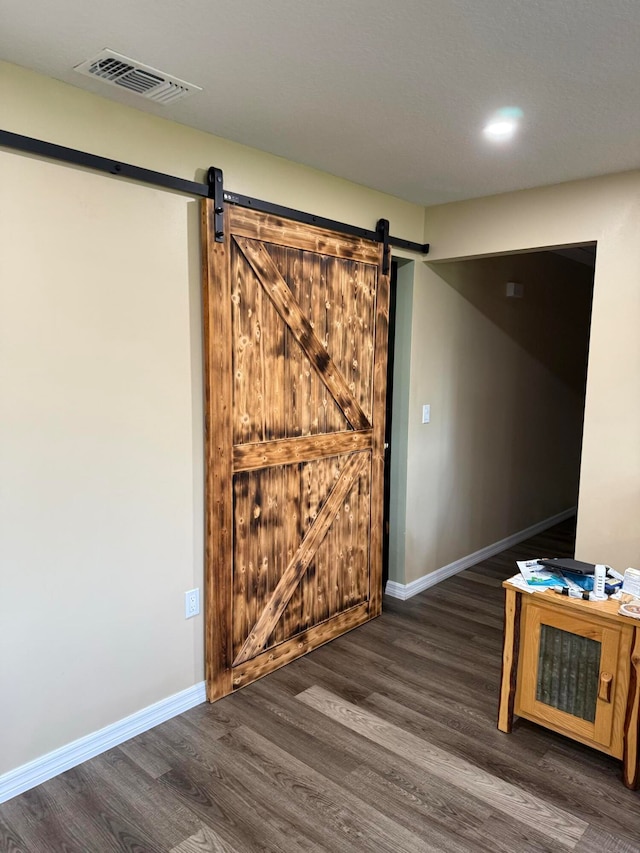 spare room featuring a barn door and dark wood-type flooring