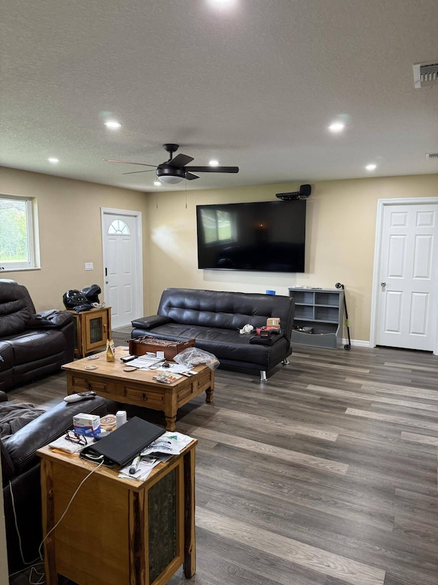 living room with a textured ceiling, ceiling fan, and dark wood-type flooring