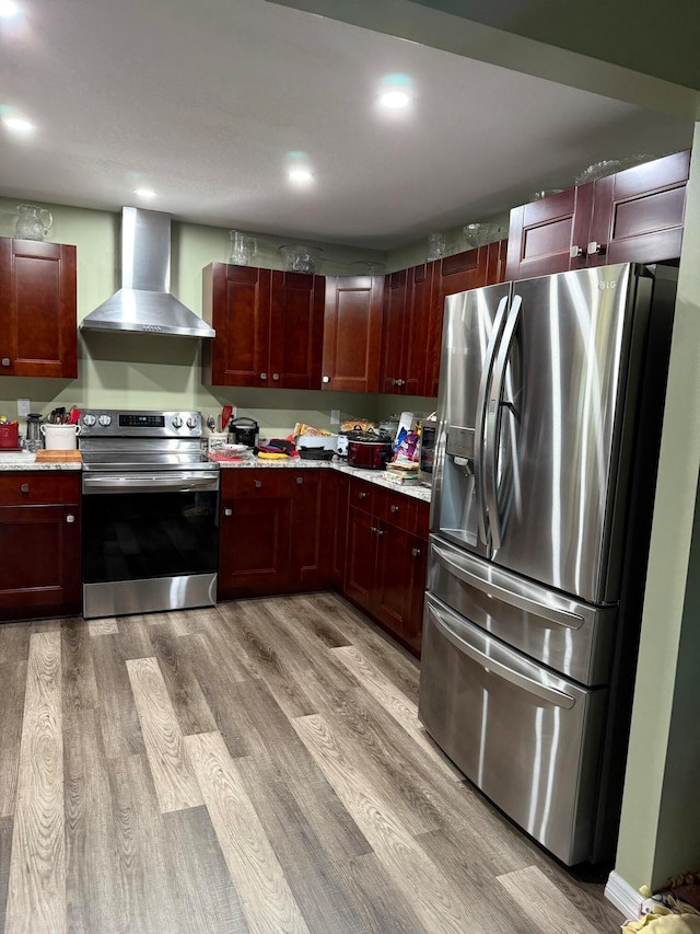 kitchen with wall chimney exhaust hood, stainless steel appliances, and light hardwood / wood-style floors