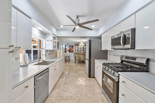 kitchen featuring backsplash, ceiling fan with notable chandelier, sink, appliances with stainless steel finishes, and white cabinetry