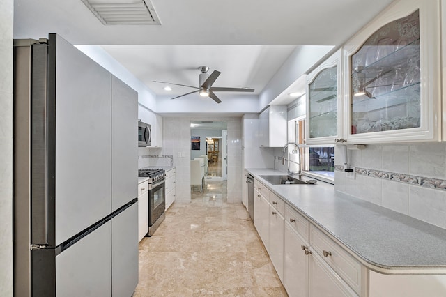 kitchen with white cabinets, sink, ceiling fan, appliances with stainless steel finishes, and tasteful backsplash