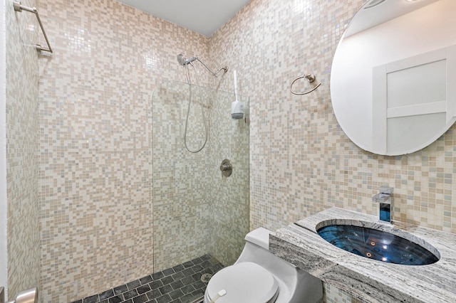 bathroom with decorative backsplash, a tile shower, sink, tile walls, and toilet