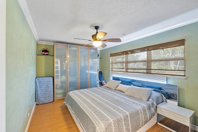 bedroom with ceiling fan, ornamental molding, a textured ceiling, and light hardwood / wood-style flooring