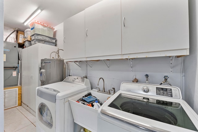 laundry room with cabinets, electric water heater, heating unit, washer and clothes dryer, and light tile patterned flooring