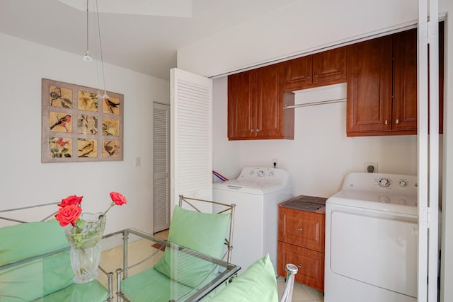 clothes washing area with cabinets, light tile patterned floors, and washer and clothes dryer