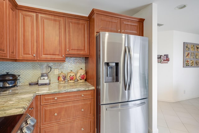 kitchen with tasteful backsplash, appliances with stainless steel finishes, light stone countertops, and light tile patterned floors