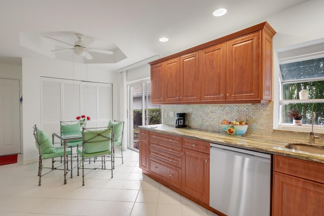 kitchen featuring tasteful backsplash, dishwasher, ceiling fan, a tray ceiling, and light stone countertops