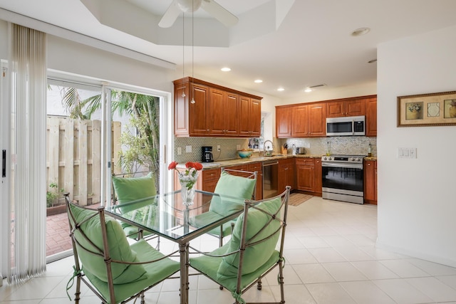 kitchen featuring sink, decorative backsplash, ceiling fan, a tray ceiling, and stainless steel appliances