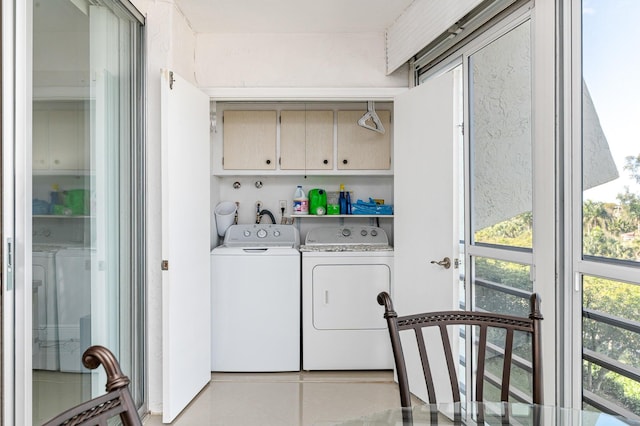 washroom featuring cabinets, a healthy amount of sunlight, and washing machine and clothes dryer