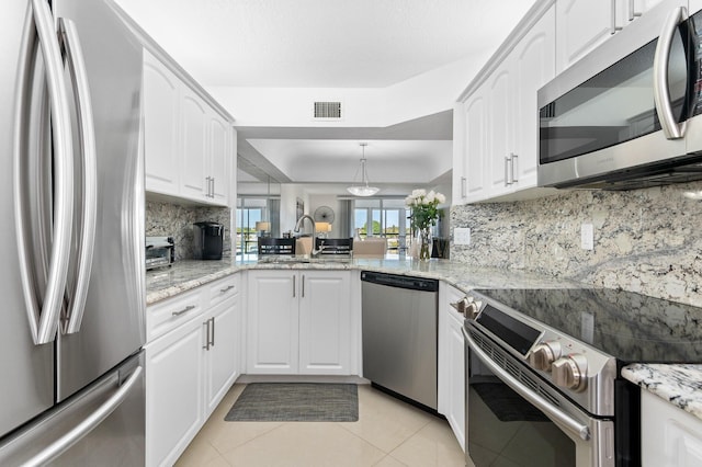 kitchen featuring kitchen peninsula, stainless steel appliances, sink, pendant lighting, and white cabinets