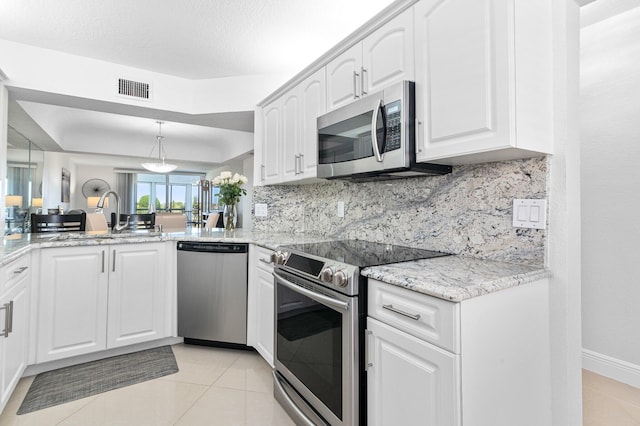 kitchen featuring decorative backsplash, stainless steel appliances, sink, light tile patterned floors, and white cabinetry