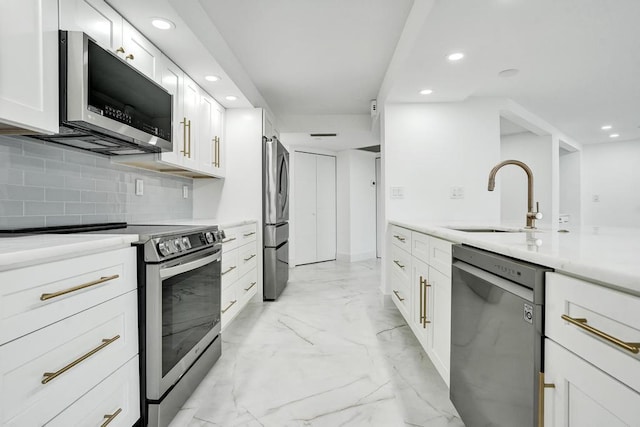 kitchen with decorative backsplash, white cabinetry, sink, and appliances with stainless steel finishes