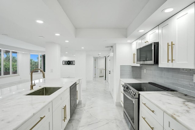 kitchen with sink, stainless steel appliances, tasteful backsplash, light stone counters, and white cabinets