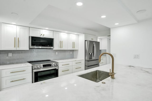 kitchen featuring decorative backsplash, light stone counters, stainless steel appliances, sink, and white cabinets