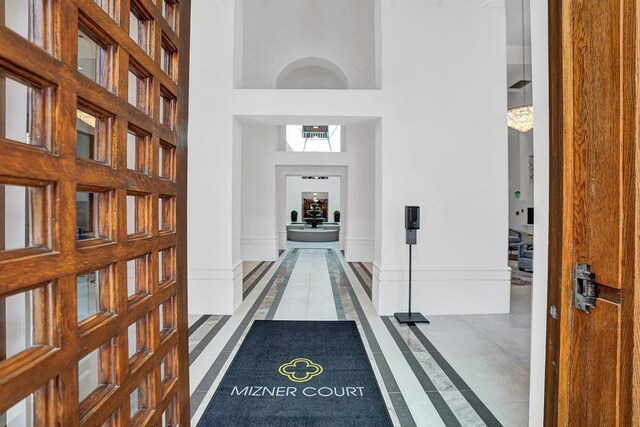 hall with tile patterned flooring and a towering ceiling